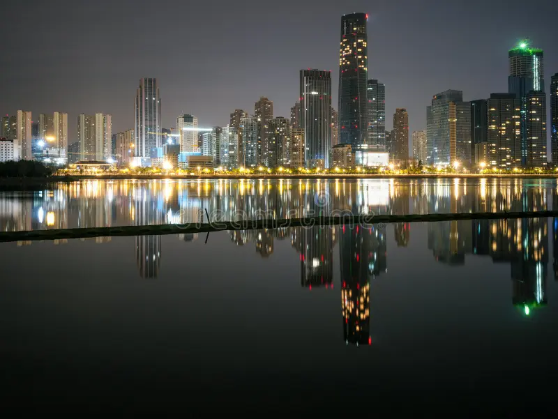 brightly-lit-modern-city-skyline-mirrored-dark-calm-water-night-brightly-illuminated-modern-skyscrapers-commercial-447834201